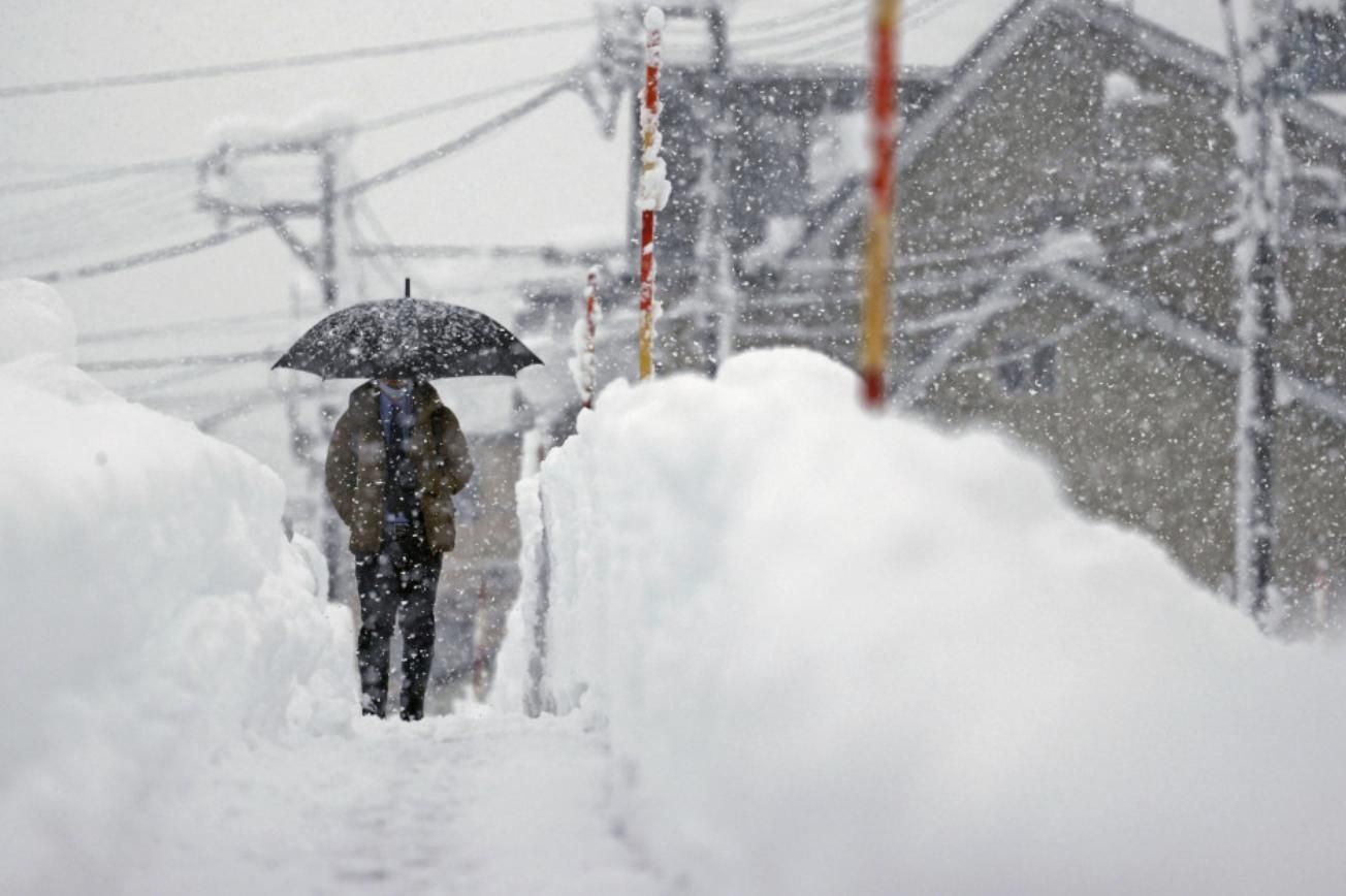 man-walks-heavy-snow-uonuma-niigata-prefecture-dec-20-2022.jpg